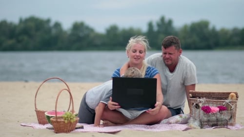Family Enjoys Time Together Using Laptop at Beach