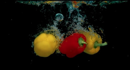 Red and Yellow Peppers Splashing into Water