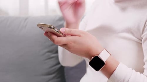 Close up of hand woman using smartphone and smartwatch in the living room for business and shopping