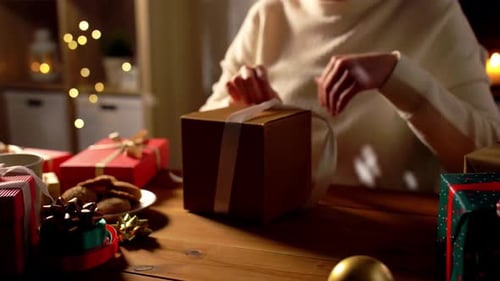 Woman Opening Christmas Gift at Cozy Table
