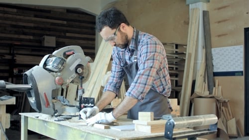 Professional Carpenter At Work Measuring Wooden Planks.