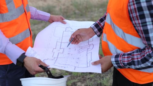Engineers Reviewing Construction Plan Outdoors