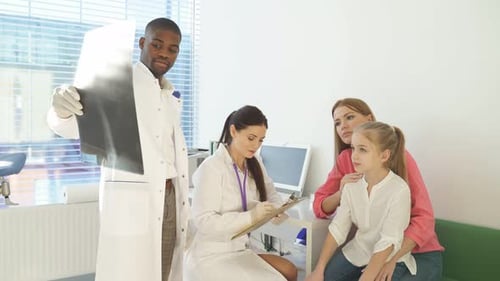 Pediatrician Explaining and Showing Lung Xray for Sick Child and Mother in Hospital Office