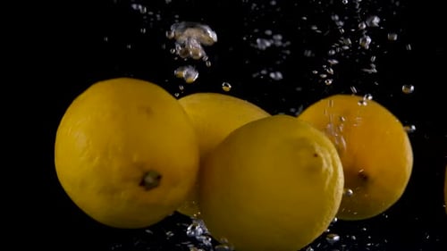 Lemons Splashing into Clear Water on Black Background