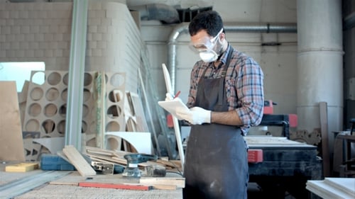 Bearded Carpenter Makes Notes In a Notebook.