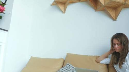 Woman Relaxes on Couch While Using Laptop