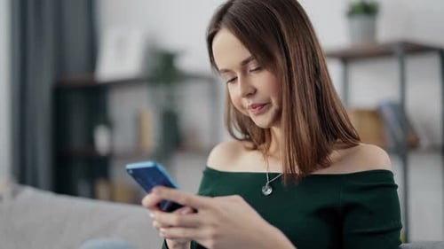 Woman Using Smart Phone on Couch at Home