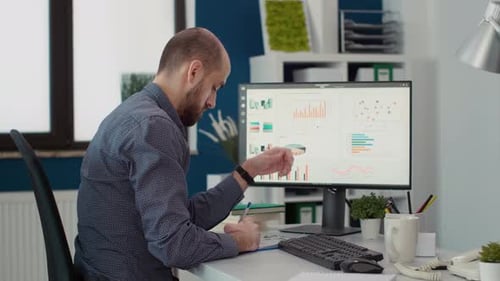 Man Analyzing Data Charts at Office Desk