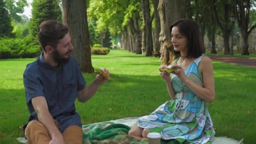 Couple Eating Sandwiches During Picnic in Park