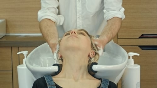 Hair Stylist Washing Woman's Hair in Salon
