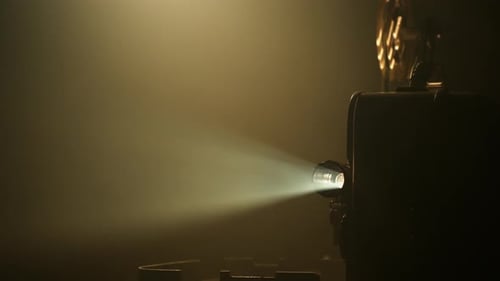 Vintage Film Projector Emitting Light in Dark Room