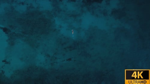 Aerial View of Two People Swimming in Teal Ocean
