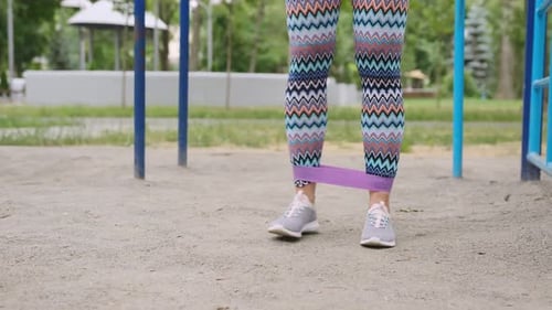 Woman Exercising Legs with Resistance Band in Park