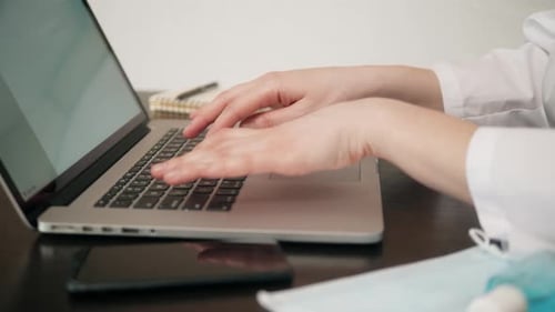 Mujer sentada en el escritorio y conectándose con su computadora portátil, ella está trabajando y escribiendo en el teclado