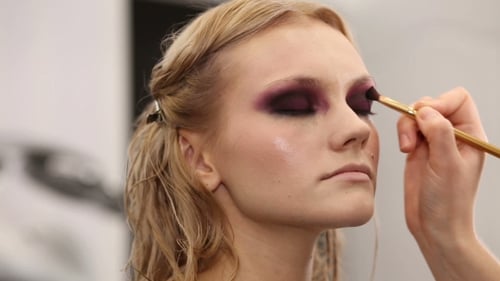 Maquillador profesional poniendo cosméticos en la cara del modelo