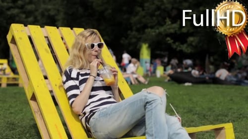 Woman Relaxes in Park on Bright Yellow Chair