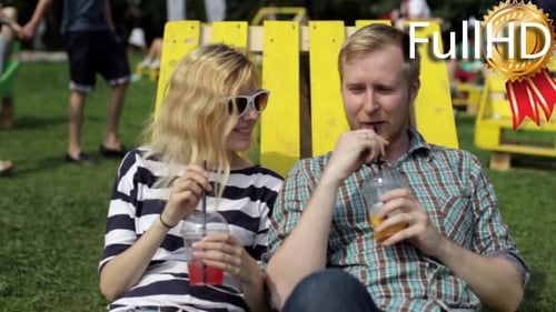 Young Couple Enjoying Drinks on Lawn in Summer