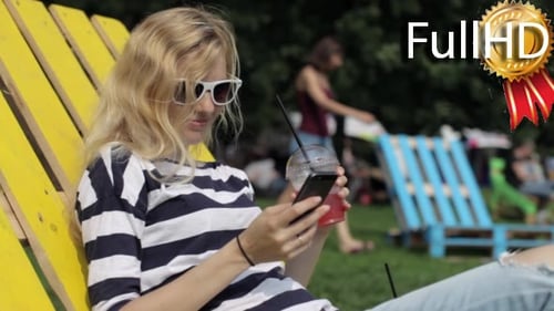 Woman Relaxing on Deck Chair Uses Smartphone
