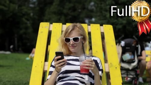 Woman On Phone Relaxing With Drink in Park