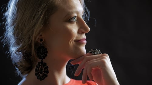 Schöne Blondine, die zur Seite schaut, Hand nah am Gesicht hält.