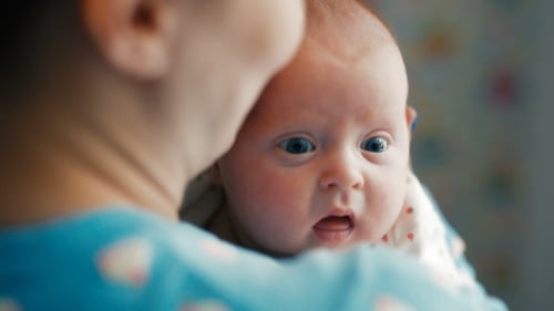 Crying Infant Being Held Indoors in Close-up