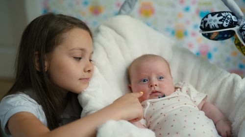 Das kleine Mädchen schaut ihre kleine Schwester an