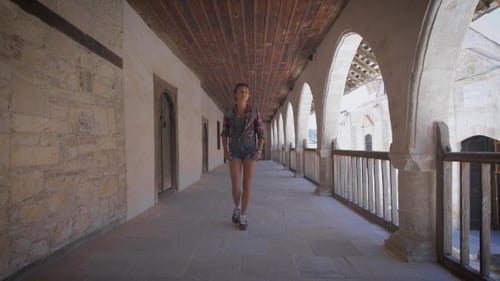 Woman Walking Along Historical Building Corridor