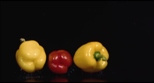 Colorful Peppers Fall on Glossy Black Surface