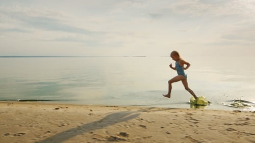Funny Girl Runs Along The Shore, Her Feet Touch The Water And Flies a Lot Of Splashing