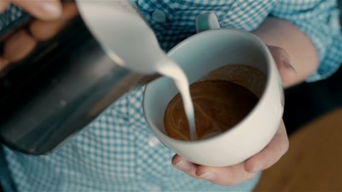 Milk Pouring into Coffee Cup Close Up