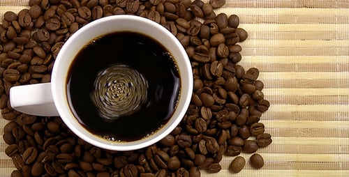 Coffee Cup Swirling on Top of Coffee Beans