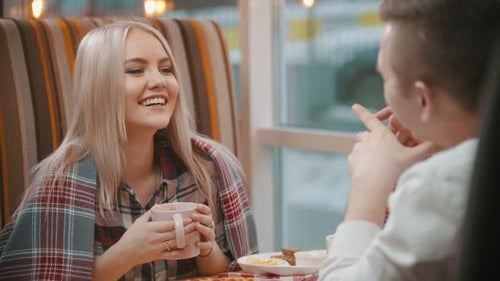 A Young Woman Drinks Coffee and Talking with Her Boyfriend in Cafe