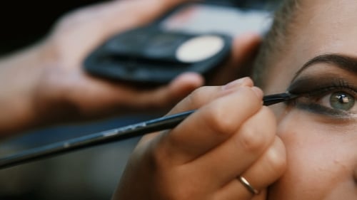 Maquilleuse faisant du maquillage professionnel de jeune femme