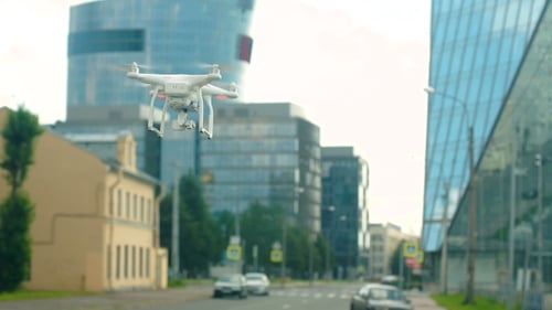 A Radio-controlled Quadcopter Hovers Over a Street In The City