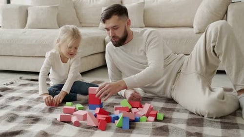 Dad and Child Play with Toy Blocks at Home