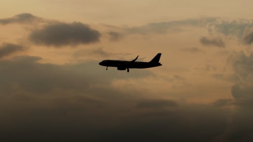 Airplane Flying Through Dramatic Sky at Sunset