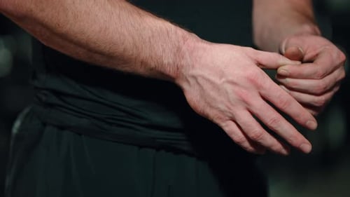 Man Stretches Fingers in a Dark Gym Setting