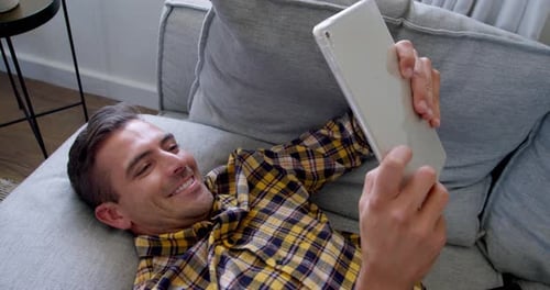 Young Man Using Tablet Relaxing on Couch