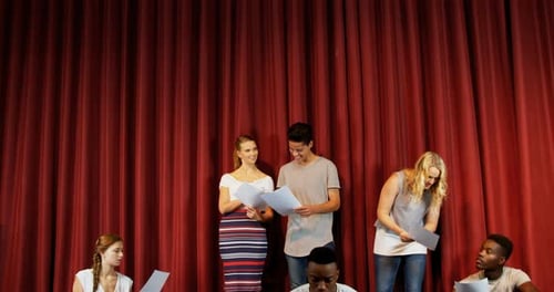 Actors reading their scripts on stage