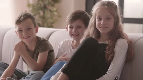 Three Smiling Children Sitting Together on a Couch