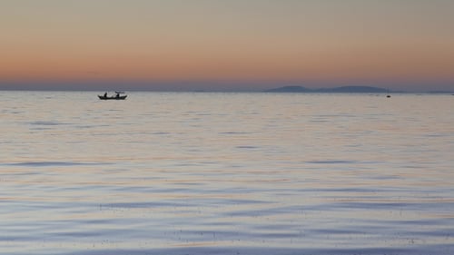 Calm Sea With a Silhouetted Rowing Boat at Sunset.