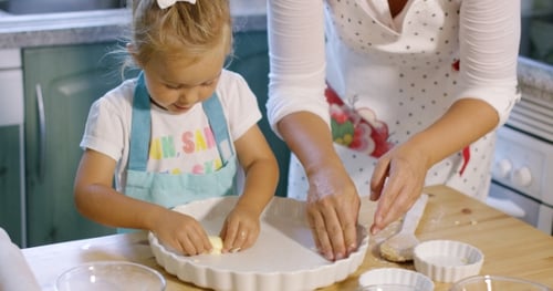 Jolie petite fille graissant un plat allant au four