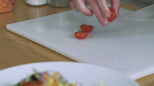 Woman Slicing Tomatoes-cherry Preparing On a Restaurant Kitchen.