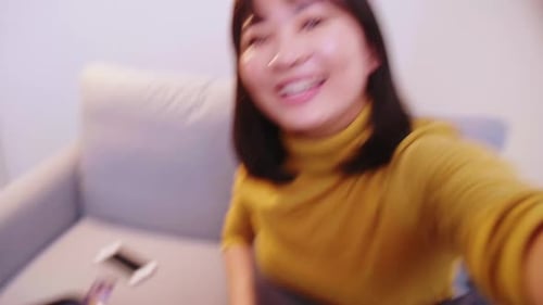 Cheerful Woman Waves to Camera Before Packing Suitcase