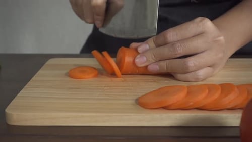 Hands Slicing Carrot on Cutting Board
