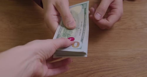 Hands Exchanging Stack of Hundred Dollar Bills