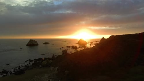 An aerial view of a spectacular sunset over a rocky ocean coastline.
