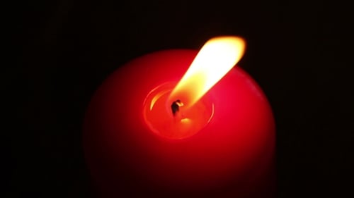 Burning Candle In Red Wax On a Dark Background