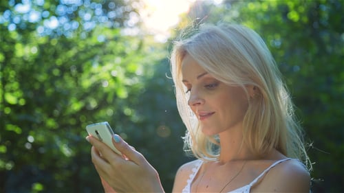 Beautiful Girl Using SmartPhone Enjoying the Sun in City Park 3
