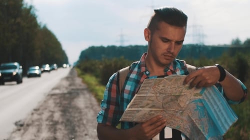 Boy With Backpack Looking In Map At Roadside. Cars. Summer Day. Talk On Phone